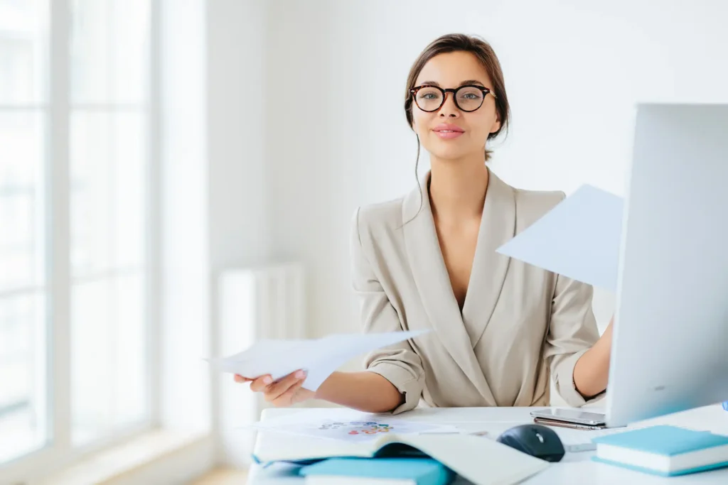 Frau mit Brille sitzt am Arbeitsplatz.